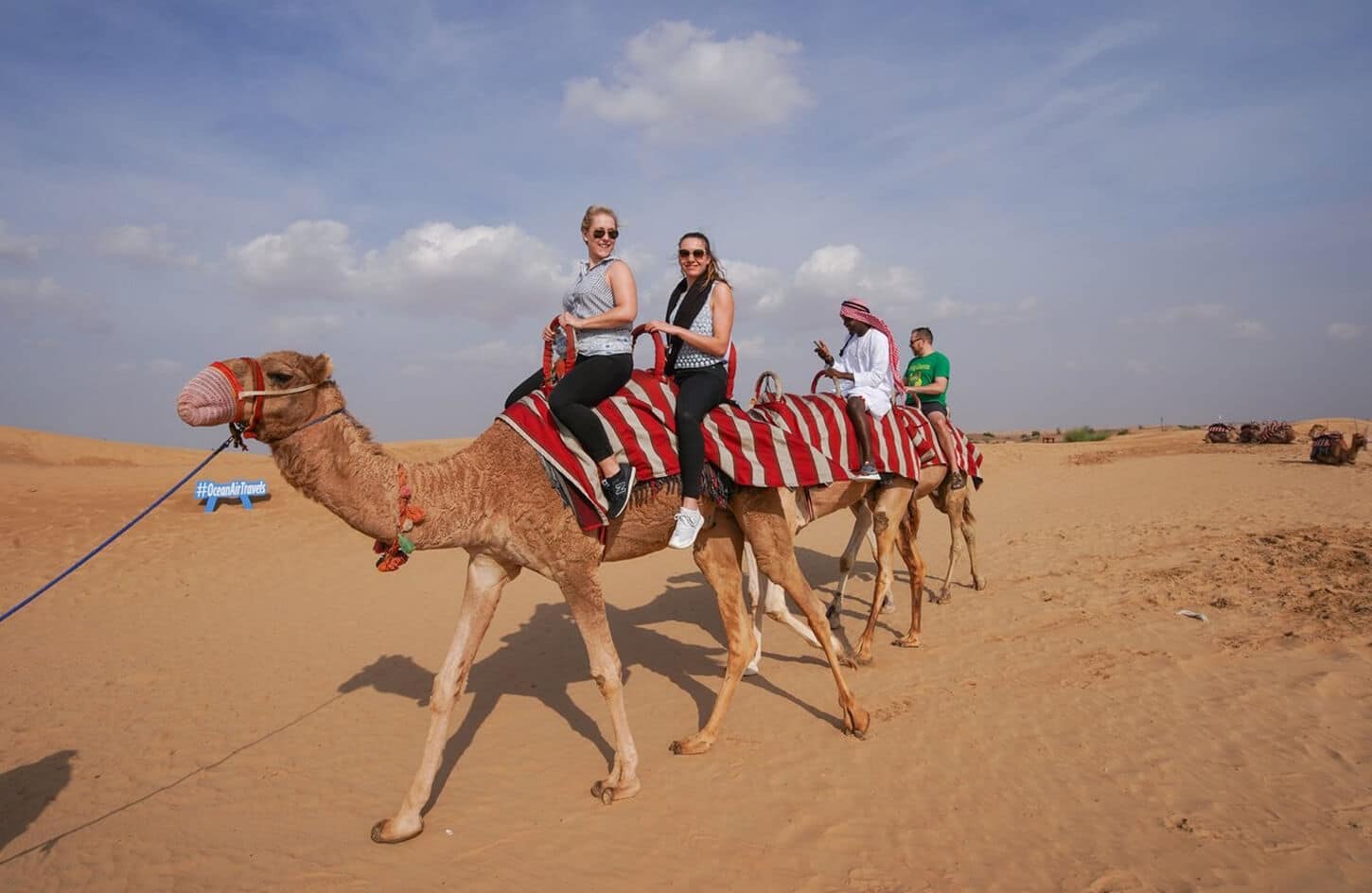 A beautiful picture of a group of tourists on camels in the Dubai desert