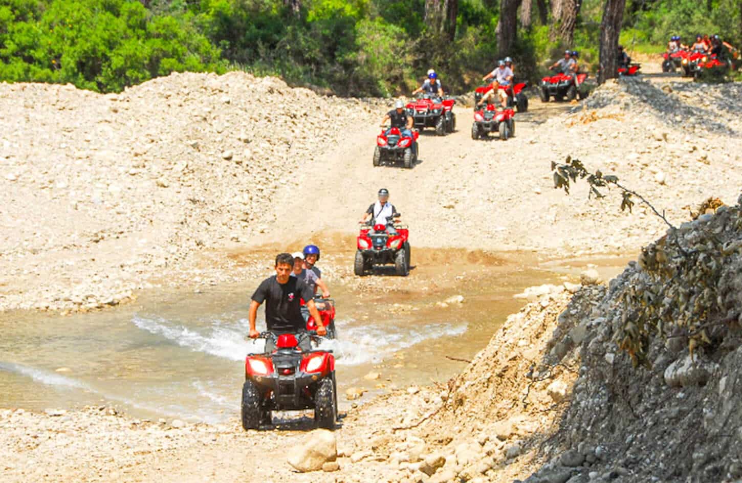 Tourists riding Quad Bikes across a muddy riverbed during an exhilarating ATV Safari Tour adventure in Turkey