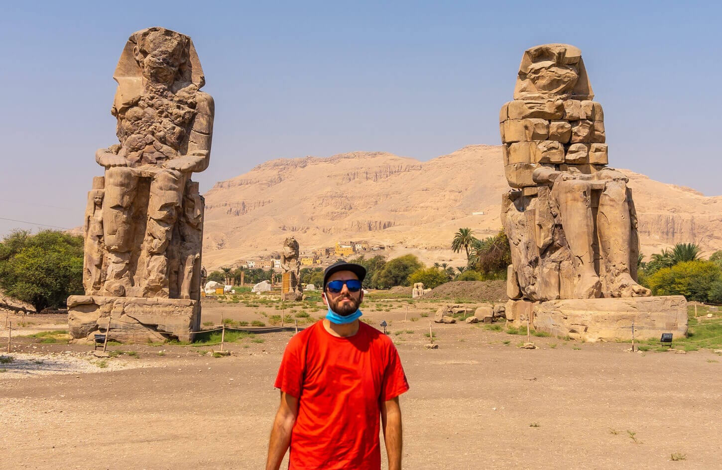 A picture of a visitor in front of the Colossi of Memnon