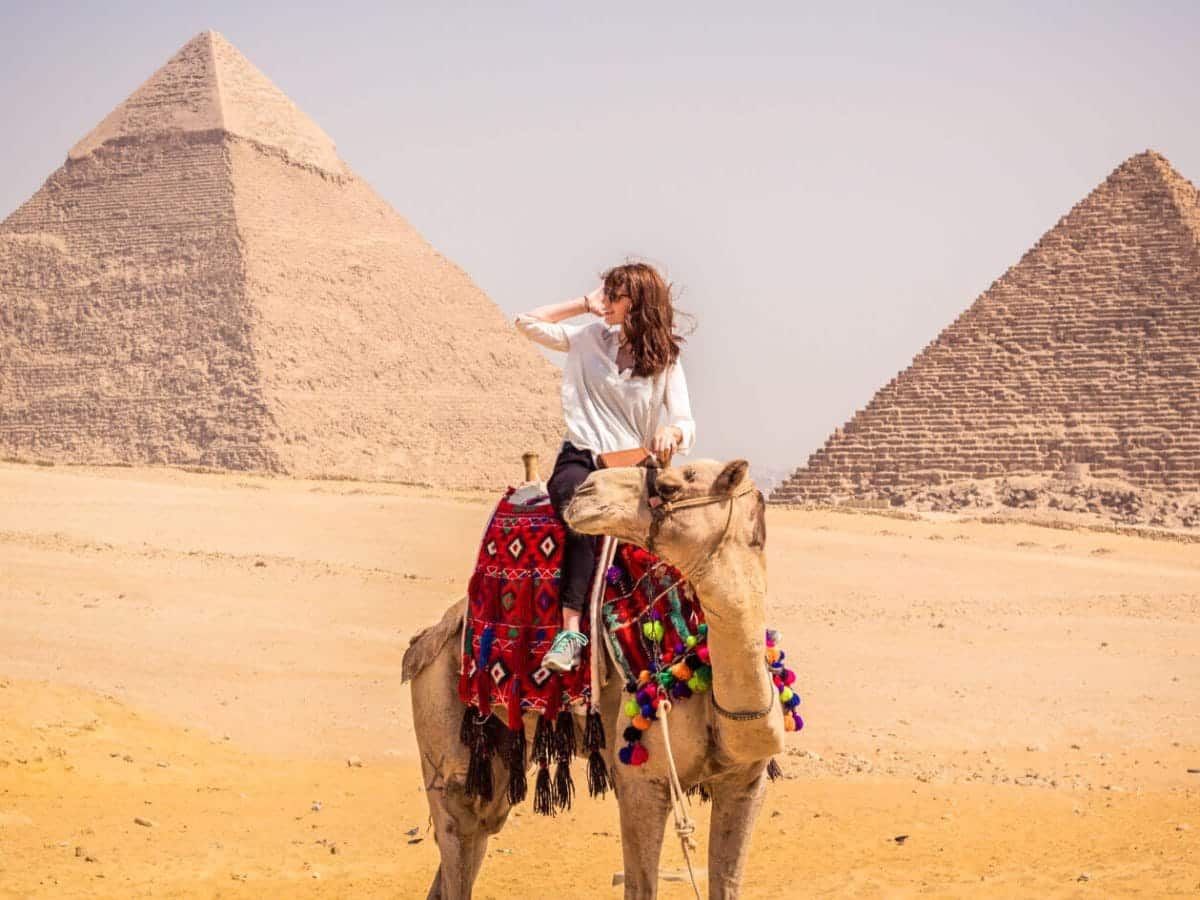 A tourist riding a camel in front of the pyramids