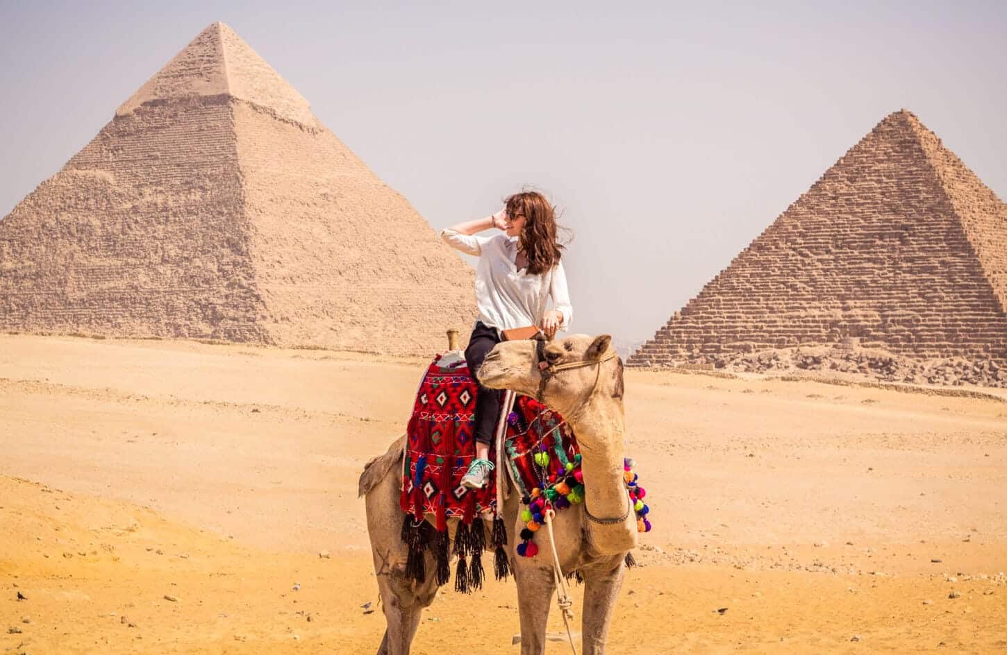 A tourist riding a camel in front of the pyramids