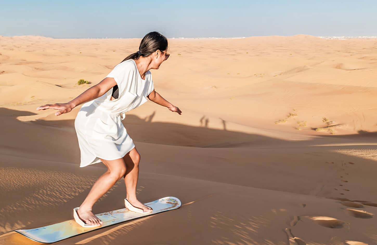 Great picture of a woman sandboarding in the desert