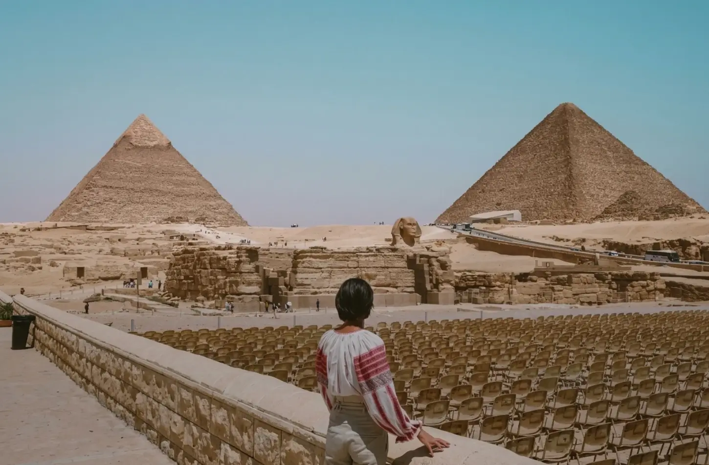 Cultural Etiquette in Egypt: The Complete Guide for Respectful Travelers 3 Female traveler dressed in modest attire admiring the Giza Pyramids and Sphinx, following cultural etiquette in Egypt.