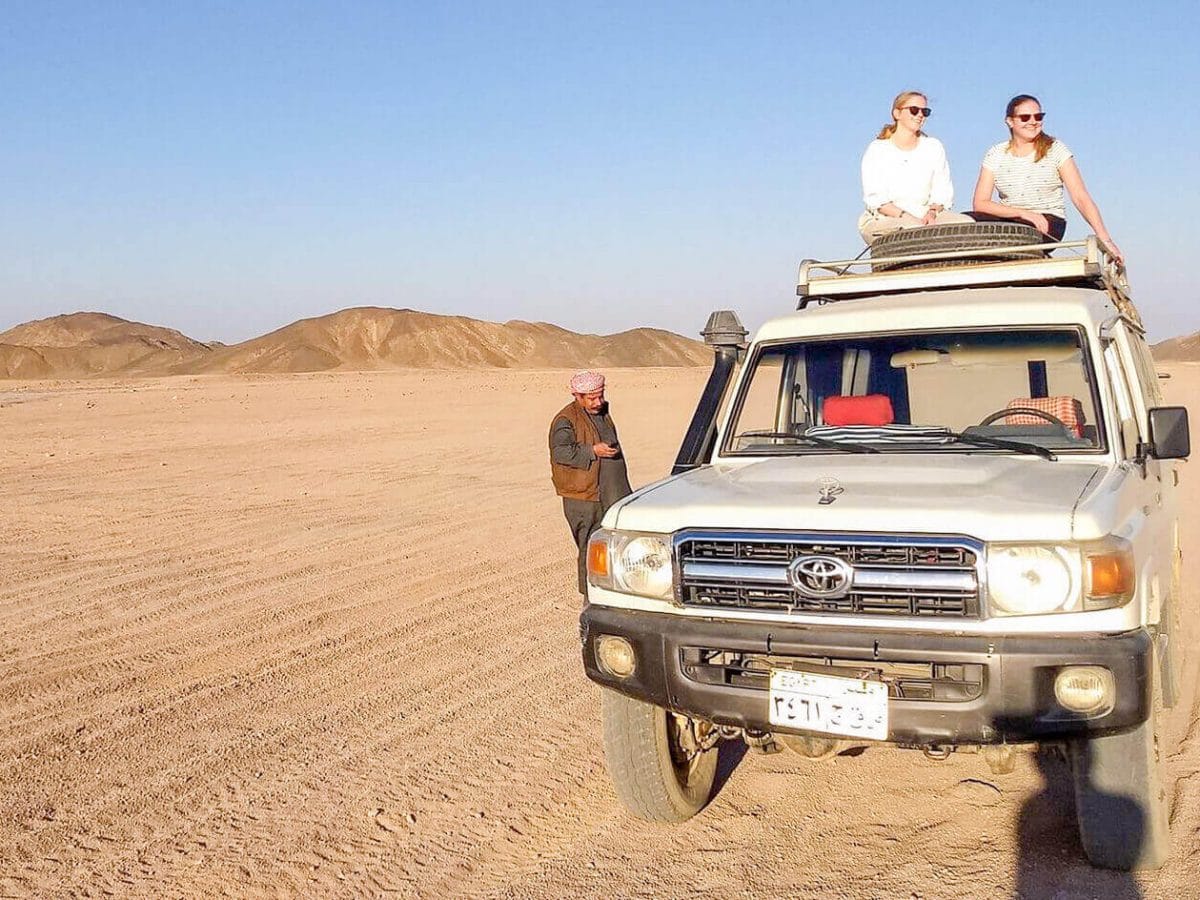 wonderful shot of two girls sitting on a four wheel drive vehicle from a safari trip