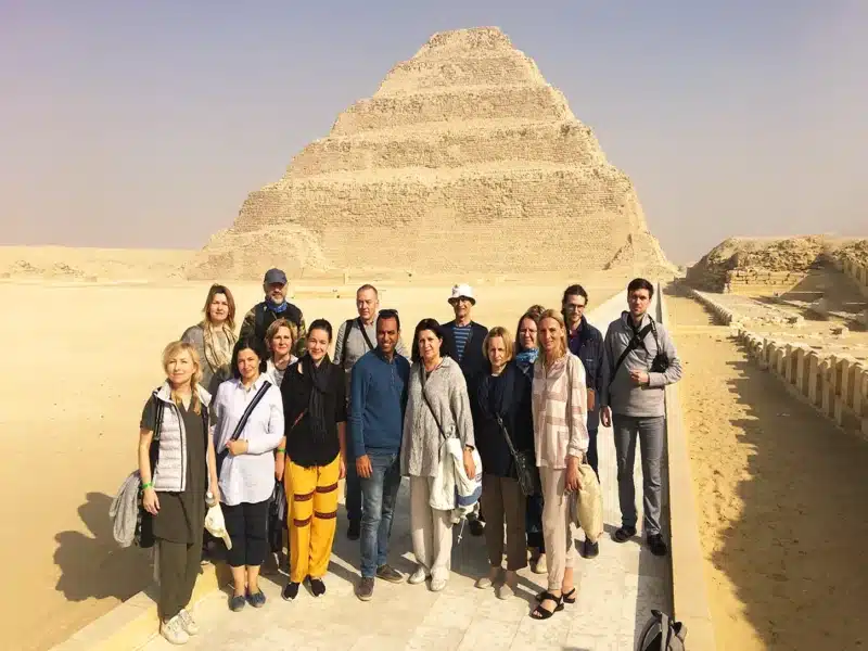 Visitors gather and pose in front of the Step Pyramid, highlighting its significance in the history of pyramid architecture.