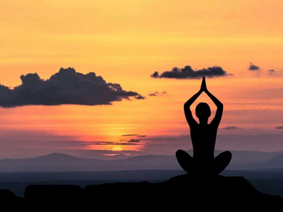 A wonderful shot of a girl meditating in front of the sunrise