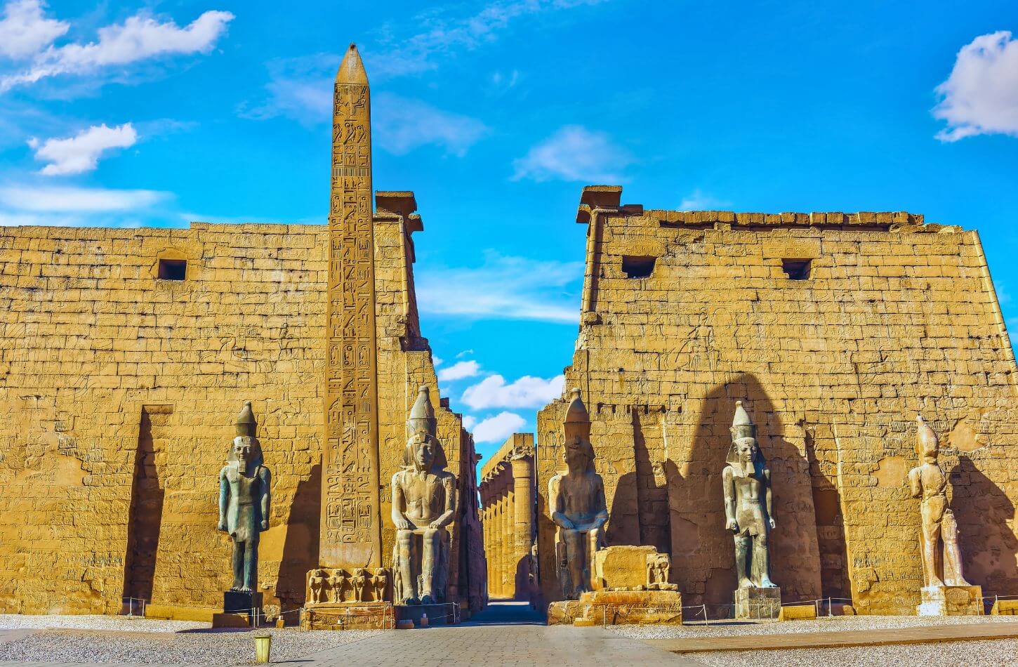 statues of ramses ii stand at the entrance to luxor temple along with the obelisk that marks the temples entrance