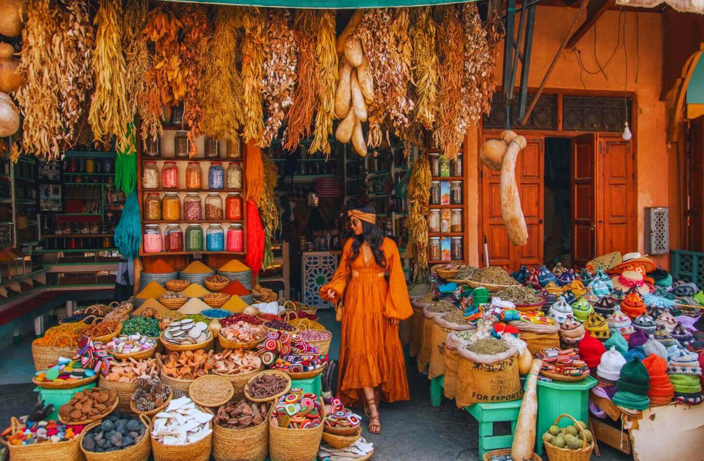 a woman explores a colorful moroccan market filled with spices herbs and traditional goods - Best Time to Visit Morocco