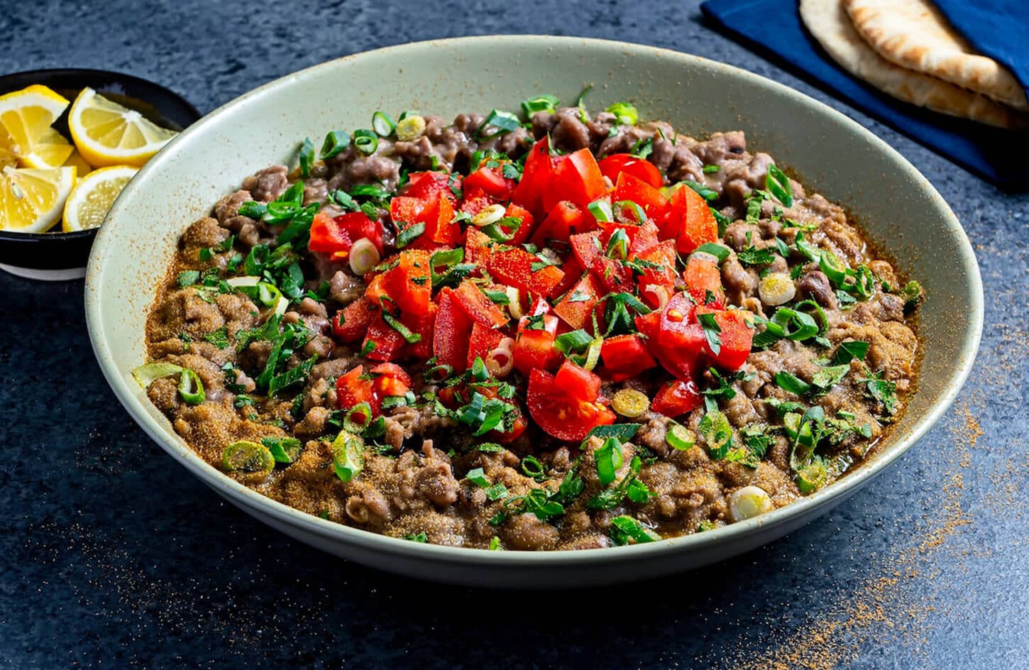 Bowl of Egyptian ful medames fava bean stew with olive oil, cumin, and warm pita bread