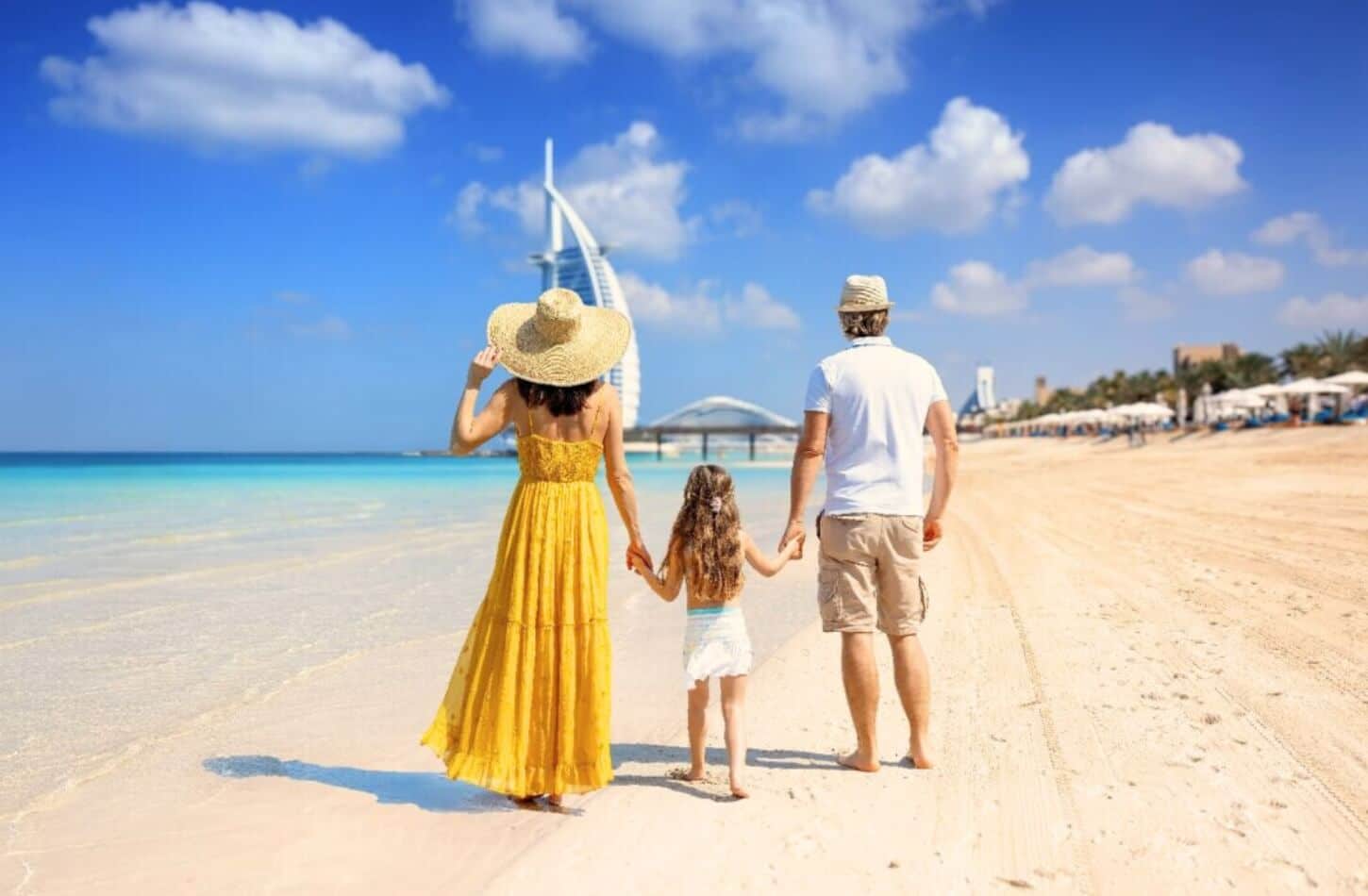 a family is walking together on a beautiful dubai beach near the burj al arab