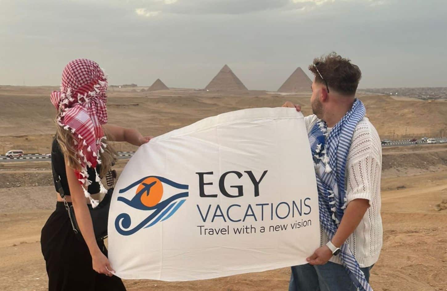 a great shot of a couple with our flag in front of the pyramids