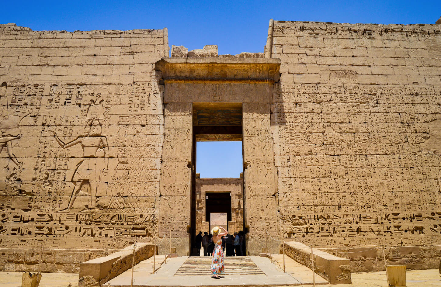 Tourist standing before the colossal pylon entrance of the Philae Temple, Aswan, Egypt.