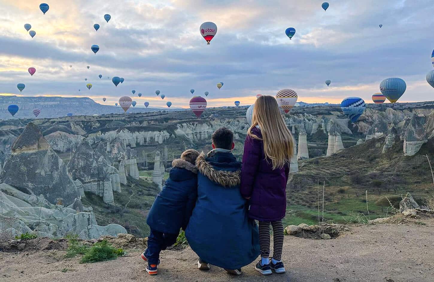 Father and children watching the hot air balloons in Cappadocia, Türkiye.