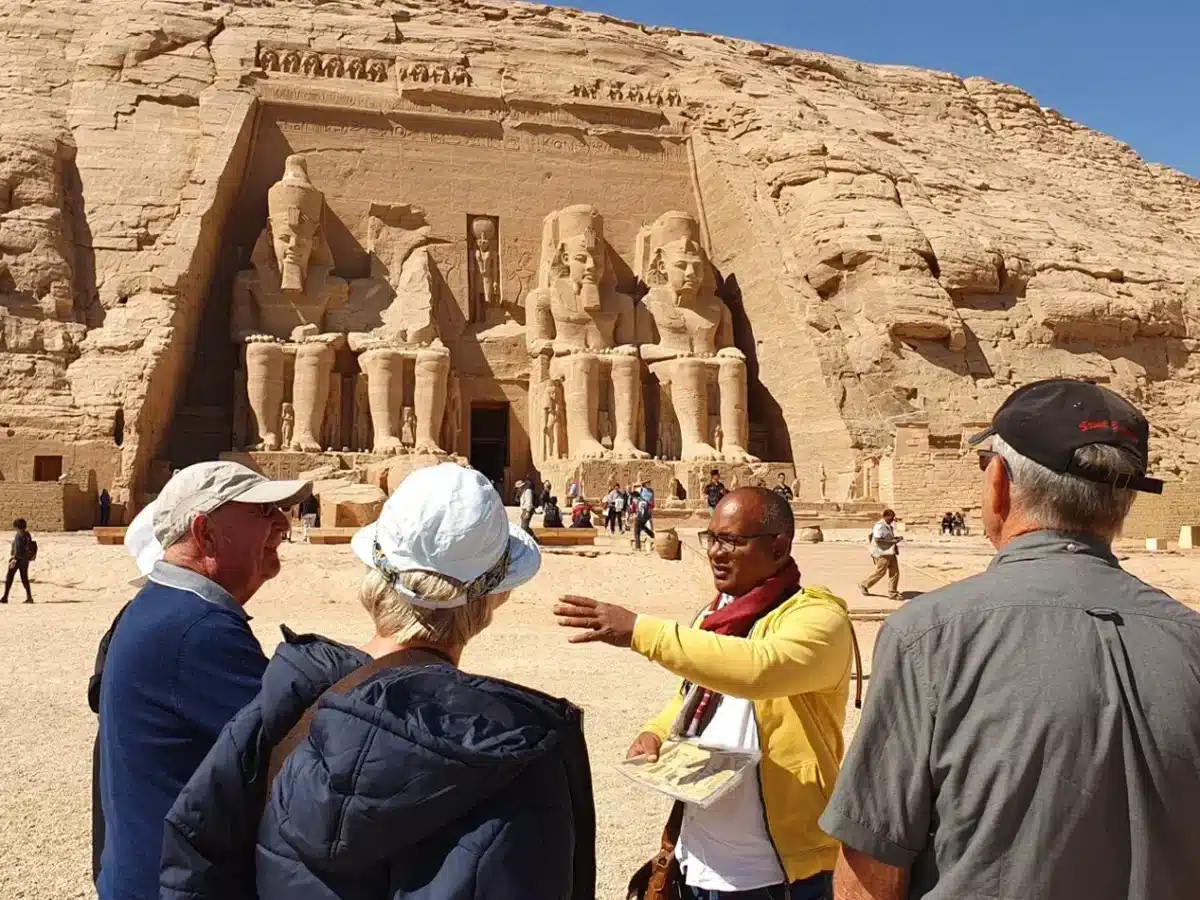 Tour guide in Egypt explaining the history of Abu Simbel Temple to tourists in front of the Ramses II statues. - Do You Need a Tour Guide in Egypt? Here's the Honest Answer
