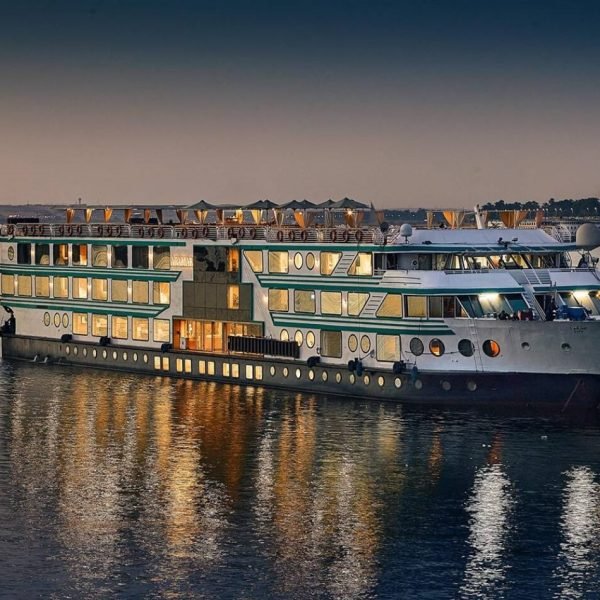 a brightly lit nile cruise ship reflecting on the calm water under the evening sky