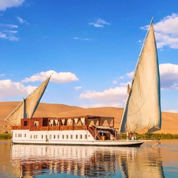 a traditional dahabiya sailing boat glides peacefully along the nile river under a bright blue sky